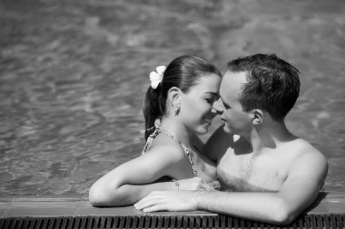 Genç ve seksi çift yüzme havuzunda sarılma. Kız geri eğilir. Arzu gözlerinin içine bakarak adam. Rüya tatil tropikal ülkede. Otelde Yüzme Havuzu