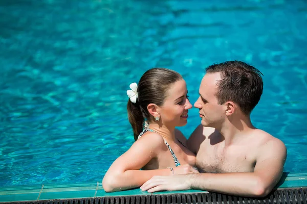 Genç ve seksi çift yüzme havuzunda sarılma. Kız geri eğilir. Arzu gözlerinin içine bakarak adam. Rüya tatil tropikal ülkede. Otelde Yüzme Havuzu