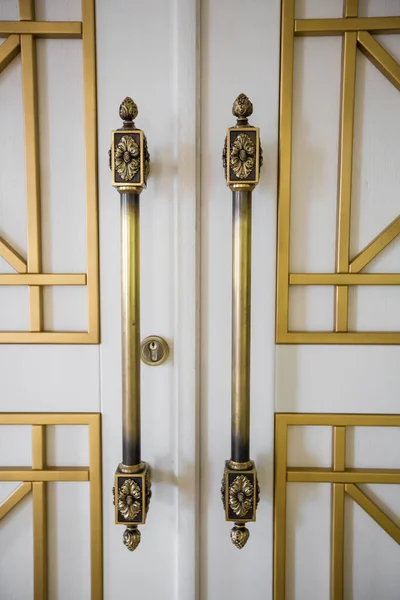 Classic vintage golden door knobs. Antique door knobs with carvings on wooden door.