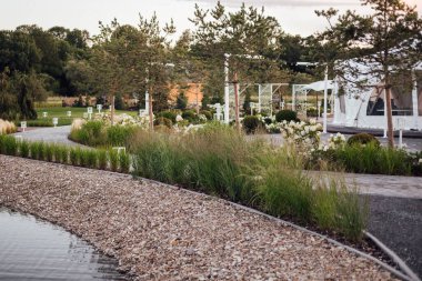 Tuğla bir duvarın arka planında çiçek tarhında yemyeşil şakayıklar. Bahçe düzenleme. Ebedi çiçekli bitkiler.