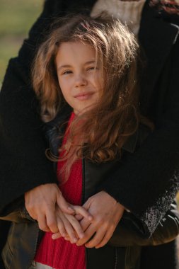 Anneye sarılan kız, sonbahar parkında, yakın plan portresi.