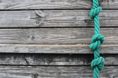 Turquoise rope with knots on a gray wooden surface
