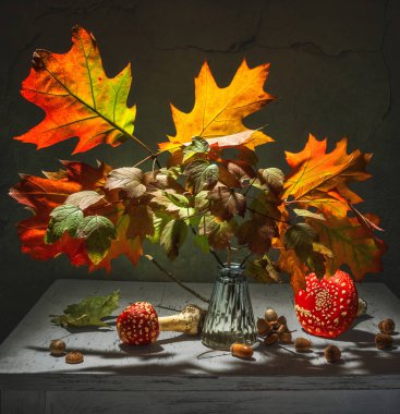 Sonbahar yapraklı meşe dalları. Kırmızı sinek agarikleri ve meşe palamutları.