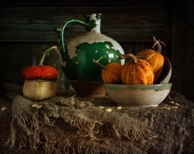 Masada olgun ve lezzetli balkabakları var. Eski, soyulmuş, seramik sürahi. Geriye dönük natürmort.