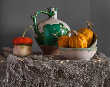 Masada olgun ve lezzetli balkabakları var. Eski, soyulmuş, seramik sürahi. Geriye dönük natürmort.