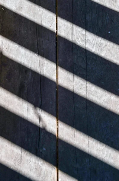 Light and shadow on old wooden boards. Light and dark lines. Abstract background. Vintage.