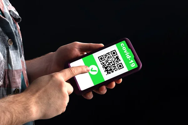 Adamın biri akıllı telefonda Coronavirus aşısı hakkında bilgi içeren bir QR kodu gösteriyor..