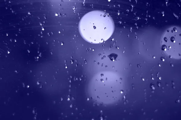 Chuva cai com efeito bokeh na cidade noturna. Gotas de chuva na janela com luzes abstratas — Fotografia de Stock