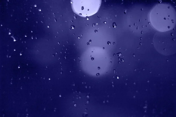 밤이 되면 도시에 는 비가 내리기 시작 합니다. 창문에는 추상적 인 불빛 이 빗방울처럼 비치고 있다 — 스톡 사진