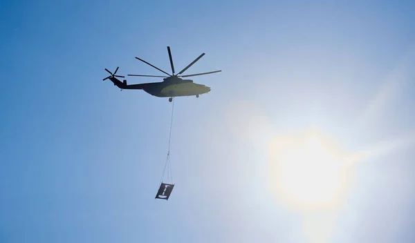 世界上最大的货运直升机在头顶盘旋 世界上最大的货运直升机用钢丝绳运送货物 底部视图 — 图库照片