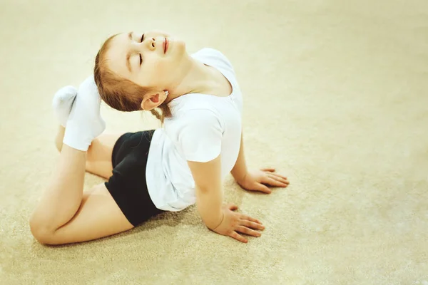 Spor salonunda egzersiz esnek küçük kız jimnastikçi akrobatik yapıyor. Spor, eğitim, fitness, yoga, aktif yaşam tarzı kavramı.
