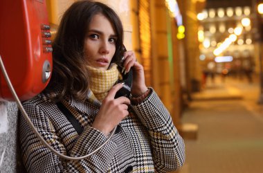 Gece bir telefon kulübesinde üzgün güzel bir kızın portresi.