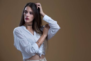 Bej arka planda beyaz gömlekli güzel bir kızın stüdyo portresi.