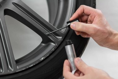 El fırçayla araba tekerleğini boyuyor. Kapatın. Beyaz bir arkaplanda izole edilmiş.