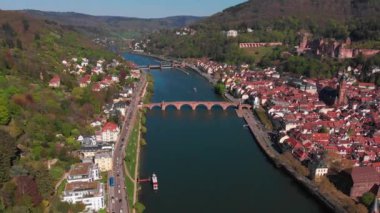 Nehrin üzerindeki yaya köprüsü. Heidelberg kalesinin ve şehrin eski kısmının güzel manzarası. Bahar. Ağaçlarda yeşil yapraklar. Nekka Nehri. Güzel dağlar.