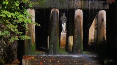 Çıplak bir kadın heykeli ve şelale. Yunan tarzında güzel sütunlar. Sarı, kırmızı yapraklar.