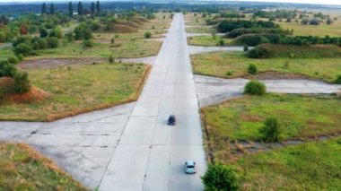 Uçak pistinde seyahat eden bir arabanın üzerinde uçmak. Kenarlarında orman ve çim var. Yukarıdan görüntüle.