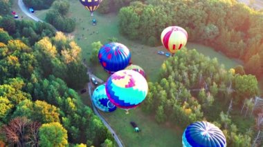Parkta uçan balonları aydınlatan güzel güneş ışınları, yeşil ağaçlar. Arka planda şehir manzarası var. Güzel sabah balonu uçuşu. Şehrin üst manzarası, orman..