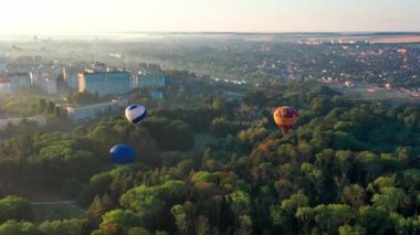 Parkın manzarası güzel, orman yeşilliklerle kaplı. Sabah nehri sisli. Arka planda küçük evler. Balon uçuşa hazırlanıyor..