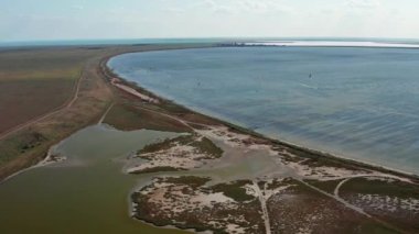 İnsanlar denizde uçurtma gibi uçuyor. Rüzgar sporcuyu deniz dalgaları boyunca taşır. Çok renkli paraşütler. Yukarıdan, bir kuadrokopterden uçurtmacılara görüntüle.