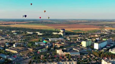 Çok renkli balonlar tarlaların, evlerin, ağaçların üzerinde uçuyor. Mavi gökyüzü. Şehrin üzerinde güzel bir yaz uçuşu. 