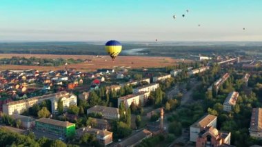 Çok renkli balonlar tarlaların, evlerin, ağaçların üzerinde uçuyor. Mavi gökyüzü. Şehrin üzerinde güzel bir yaz uçuşu. 