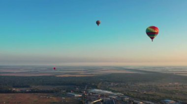 Çok renkli balonlar tarlaların, evlerin, ağaçların üzerinde uçuyor. Mavi gökyüzü. Şehrin üzerinde güzel bir yaz uçuşu.