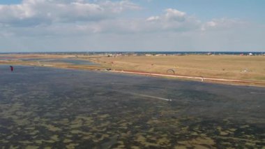 İnsanlar denizde uçurtma gibi uçuyor. Rüzgar sporcuyu deniz dalgaları boyunca taşır. Çok renkli paraşütler. Yukarıdan, bir kuadrokopterden uçurtmacılara görüntüle.