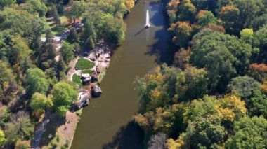 Ağaçların üzerinde güzel bir uçuş. Sonbahar ormanı. Ağaçlarda sarı, kırmızı, yeşil yapraklar. Güzel bir göl ve çeşme manzarası..