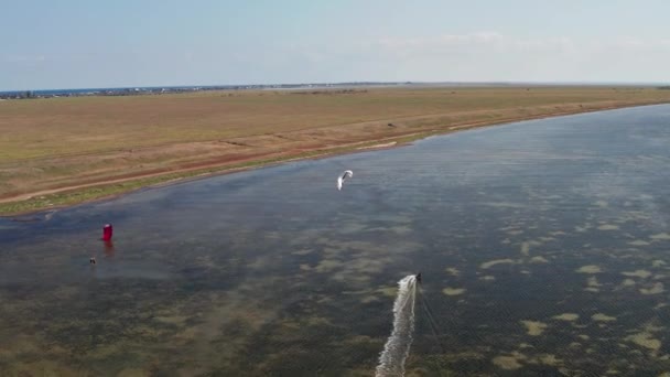 人々は海でカイトサーフィンに行く 風が海の波に沿って選手を運ぶ 多色のパラシュート — ストック動画