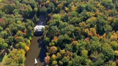Ağaçların üzerinde güzel bir uçuş. Sonbahar ormanı. Ağaçlarda sarı, kırmızı, yeşil yapraklar. Güzel bir göl ve çeşme manzarası..