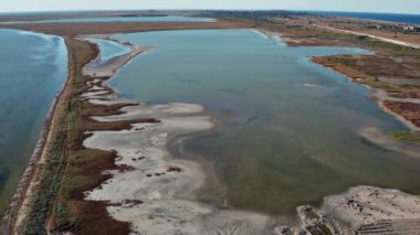 Yazın sahilde güzel bir uçuş. İnsanlar deniz kenarında dinleniyor. Turistler için evler. Plaj şemsiyeleri, gezintiler, denizde yüzen insanlar..