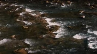 Fast flow of water on a mountain river. Beautiful mountain river. Brown stones are visible in the transparent mountain river.