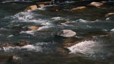 Fast flow of water on a mountain river. Beautiful mountain river. Brown stones are visible in the transparent mountain river.