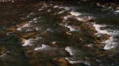 Fast flow of water on a mountain river. Beautiful mountain river. Brown stones are visible in the transparent mountain river.