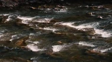 Fast flow of water on a mountain river. Beautiful mountain river. Brown stones are visible in the transparent mountain river.