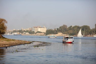Luxor, Egypt - January 17, 2019: Beautiful fishing and pleasure boats on the Nile in Luxor. Beautiful river and reflections of boats in the water. Clear, sunny day.