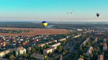Çok renkli balonlar ağaçların üzerinde uçar. Parkın manzarası güzel, orman yeşilliklerle kaplı. Güzel mavi gökyüzü ve şehrin üst manzarası, evler..