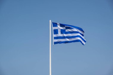 Yunanistan 'ın işareti. Bayrak direğindeki Yunan bayrağı rüzgarda dalgalanıyor. Açık mavi gökyüzü, Atina 'da güneşli bir bahar günü.