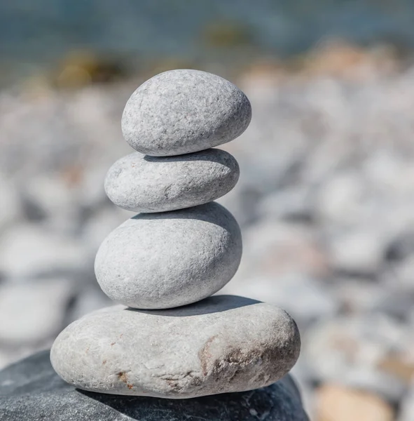 Feng shui, harmony and peace concept. Balance, zen stones, smooth rock tower stacked on pebble beach, blue sea background, sunny day.