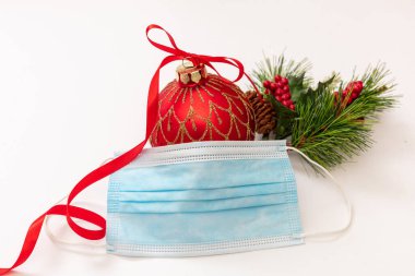 Kış sezonu tatil etkinlikleri ve güvenlik içinde kutlama. Coronavirus 'ta yeni yıl ve Noel. Xmas dekorasyon ve COVID 19 koruyucu maske beyaz arkaplanda izole.
