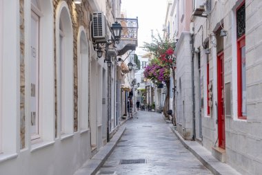 Syros adasının başkenti Cyclades 'teki Ermoupolis köyü kaldırım taşı caddesi, yaz turistik beldesi Yunanistan. Geleneksel binalar kafe dükkanları begonviller fenerler balkonlar misafirperver insanlar.