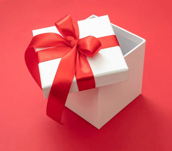 圣诞礼盒白色 红丝带蝴蝶结 红色背景 情人节惊喜 新年礼物 缎子卷曲装饰 — 图库照片