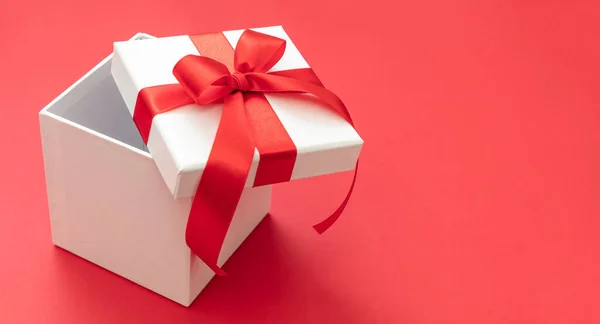 圣诞礼品盒白色 红色丝带蝴蝶结 红色背景 情人节惊喜 新年礼物 缎子卷曲装饰 复制空间 贺卡模板 — 图库照片