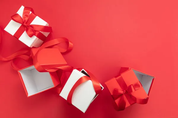 圣诞礼物惊喜 新年礼品盒缎子卷曲装饰 尽收眼底 假日准备工作 白色和红色包带弓开和关闭红色背景 — 图库照片