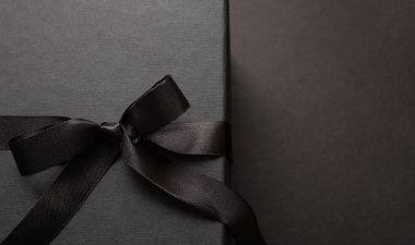 Kara Cuma indirim konsepti, kurdele yayı ile bağlanmış hediye kutusu siyah arka plan, yakın görüş, boşluk. Kış mevsiminde tatil promosyonu şablon, üst görünüm