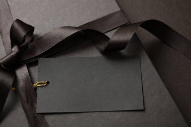 Kara Cuma indirimi konsepti, hediye kutusu detay kurdelesi yayı ve siyah arka planda boş etiket. Kış mevsiminde tatil promosyonu şablon, alan sunar