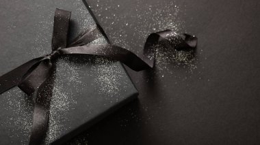 Kara arka planda kurdeleli hediye kutusu, Kara Cuma indirim konsepti, kış tatili promosyonu, üst görünüm.