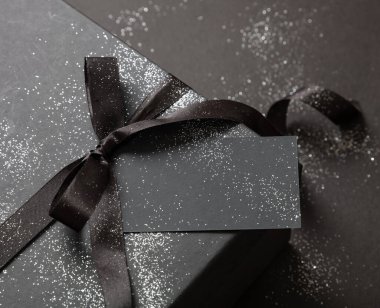 Kara Cuma indirimi konsepti, hediye kutusu detay kurdelesi yayı ve siyah arka planda boş etiket. Kış mevsiminde tatil promosyonu şablon, alan sunar