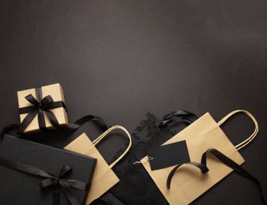 Kara Cuma indirim konsepti, hediye kutuları ve siyah arka planda bağlı kurdele torbaları, üst manzara, kış tatili promosyonu